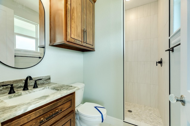 bathroom featuring toilet, a tile shower, and vanity