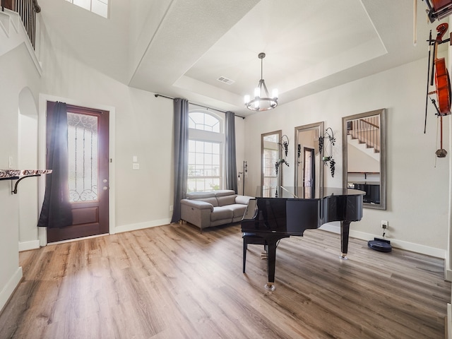 misc room with a notable chandelier, wood-type flooring, and a tray ceiling