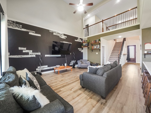 living room with ceiling fan, wood-type flooring, and a towering ceiling