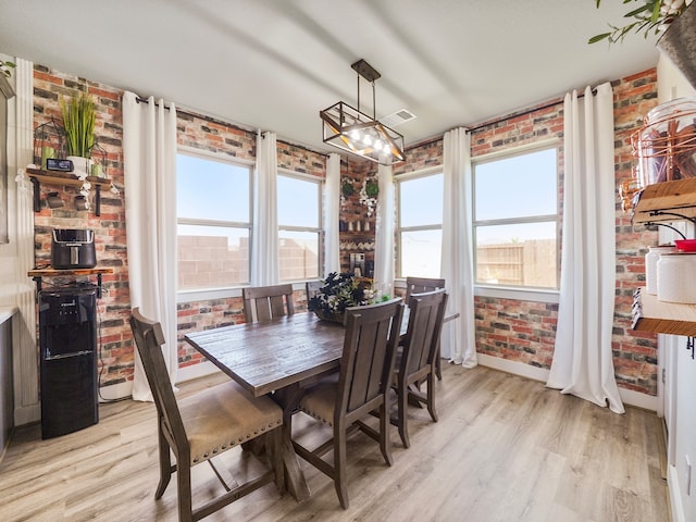 dining space featuring brick wall and light hardwood / wood-style flooring