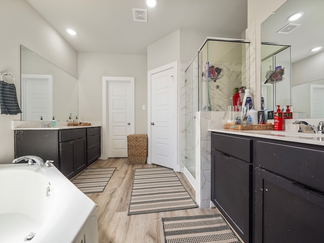 bathroom with plus walk in shower, dual vanity, and wood-type flooring