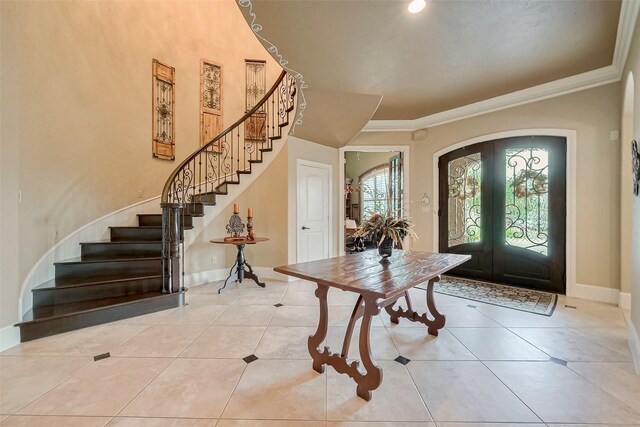 tiled foyer entrance with crown molding and french doors