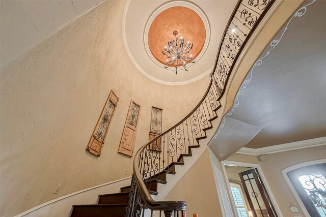 staircase featuring a chandelier, crown molding, and a towering ceiling