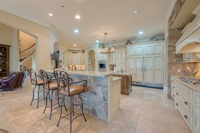 kitchen featuring stainless steel appliances, backsplash, decorative light fixtures, crown molding, and a kitchen island with sink