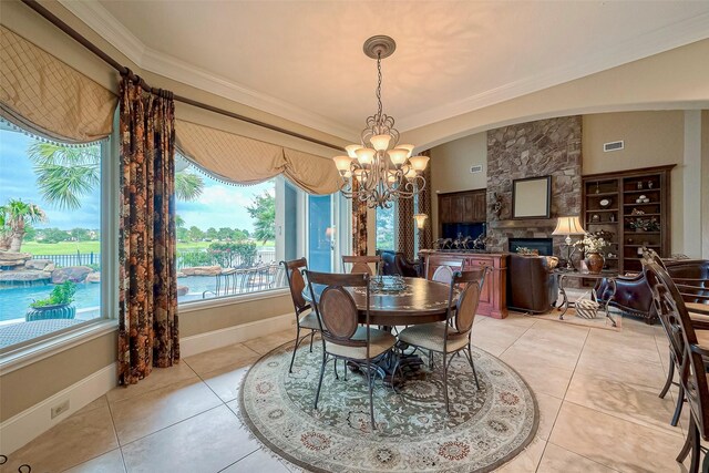 dining area featuring an inviting chandelier, a fireplace, light tile patterned floors, and a water view