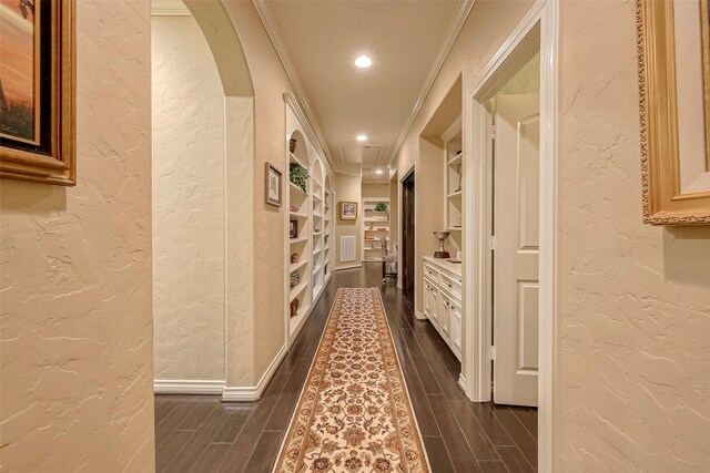 corridor featuring dark hardwood / wood-style floors, built in shelves, and ornamental molding