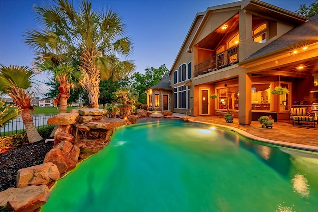 pool at dusk with a patio area