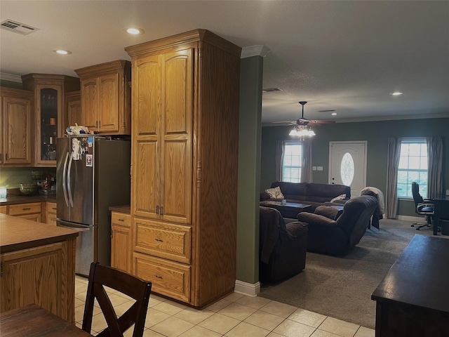 kitchen with stainless steel refrigerator, ornamental molding, light carpet, and a healthy amount of sunlight