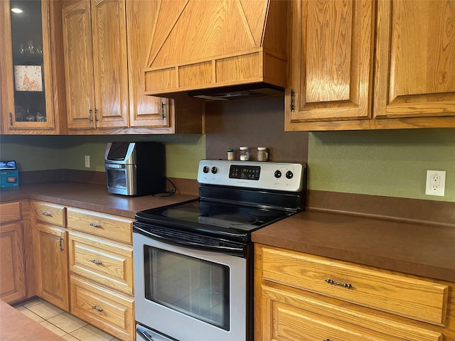 kitchen featuring custom exhaust hood, light tile patterned floors, and stainless steel range with electric cooktop