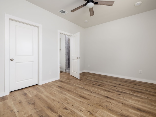 unfurnished bedroom with hardwood / wood-style flooring, connected bathroom, and ceiling fan