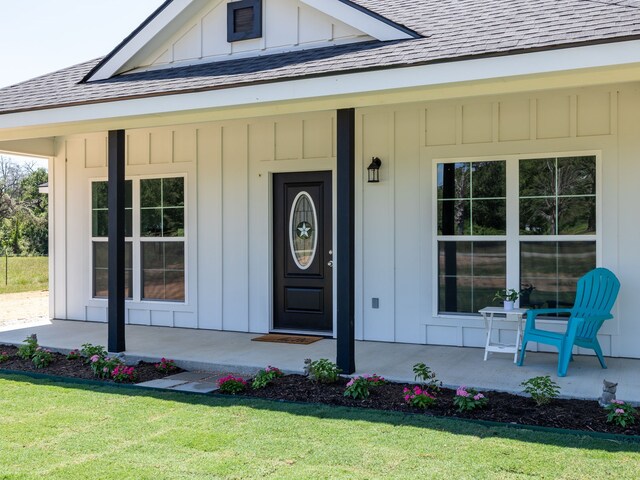 doorway to property with a porch and a yard