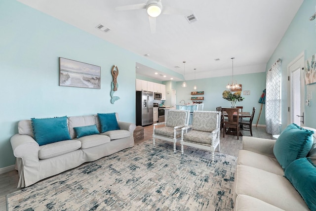 living room featuring ceiling fan with notable chandelier and light hardwood / wood-style floors