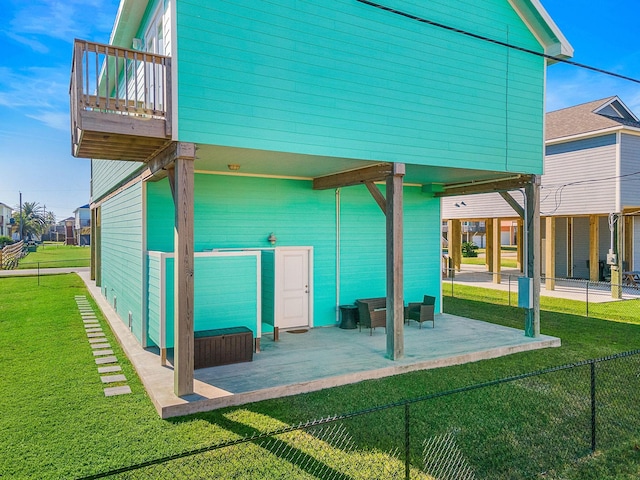 rear view of property featuring a balcony, a yard, and a patio area