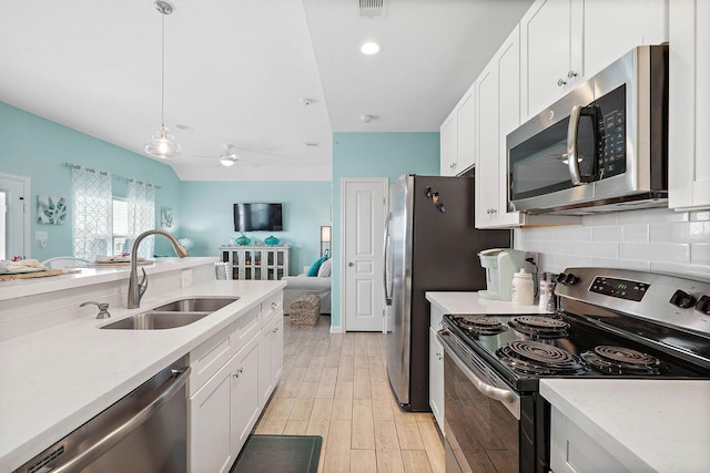 kitchen featuring stainless steel appliances, hanging light fixtures, sink, and white cabinets