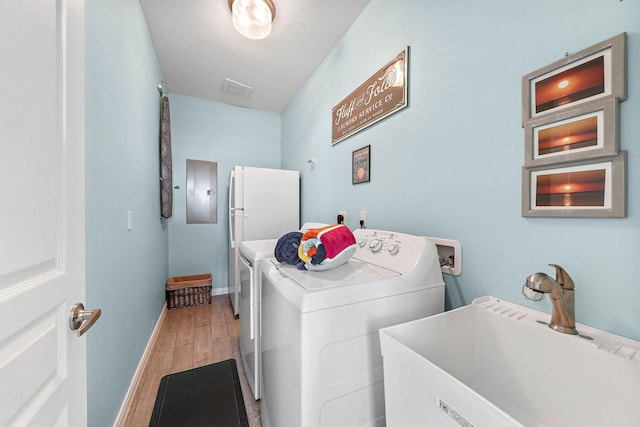 laundry room featuring sink, hardwood / wood-style floors, electric panel, and washer and clothes dryer