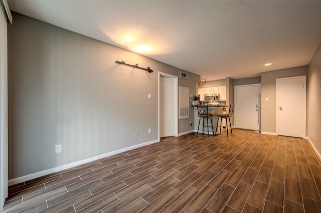 unfurnished living room featuring dark hardwood / wood-style floors and a textured ceiling