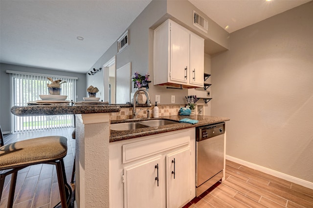 kitchen with white cabinets, sink, tasteful backsplash, dishwasher, and dark stone countertops