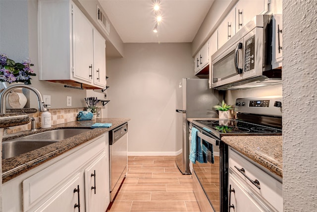 kitchen featuring stainless steel appliances, sink, white cabinetry, light hardwood / wood-style flooring, and stone counters