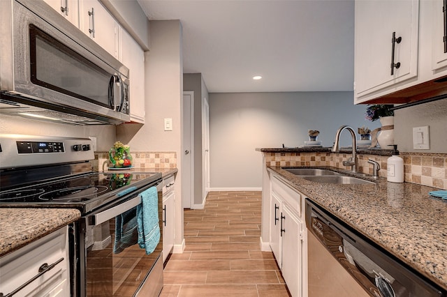 kitchen featuring light stone countertops, white cabinets, sink, light hardwood / wood-style floors, and appliances with stainless steel finishes