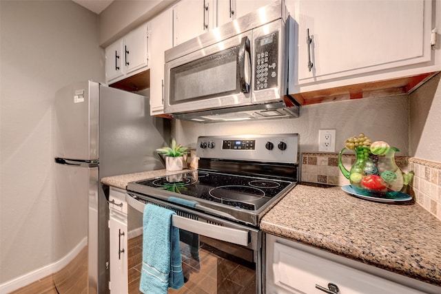 kitchen with light stone countertops, white cabinetry, stainless steel appliances, and backsplash