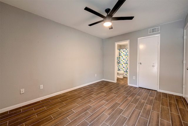 unfurnished bedroom featuring ceiling fan, ensuite bath, and dark hardwood / wood-style flooring