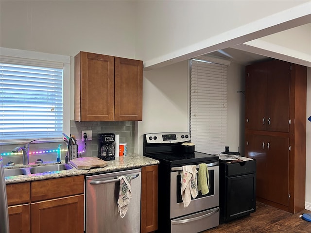 kitchen featuring light stone countertops, appliances with stainless steel finishes, backsplash, dark wood-type flooring, and sink