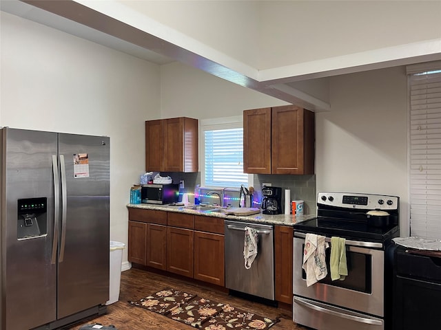 kitchen featuring dark wood-type flooring, sink, light stone countertops, appliances with stainless steel finishes, and tasteful backsplash