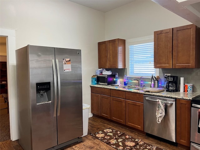 kitchen with light stone countertops, sink, dark hardwood / wood-style flooring, backsplash, and appliances with stainless steel finishes