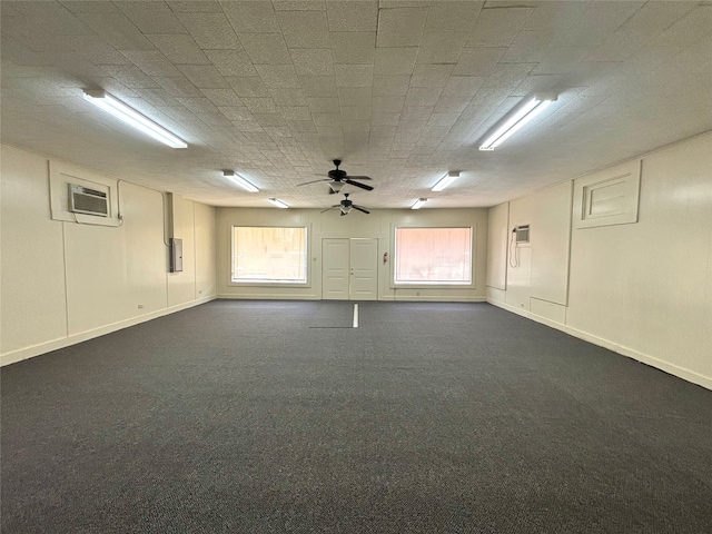 basement with electric panel, a wall mounted air conditioner, dark colored carpet, and ceiling fan