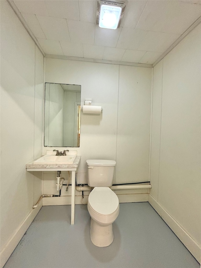 bathroom featuring concrete floors, sink, and toilet