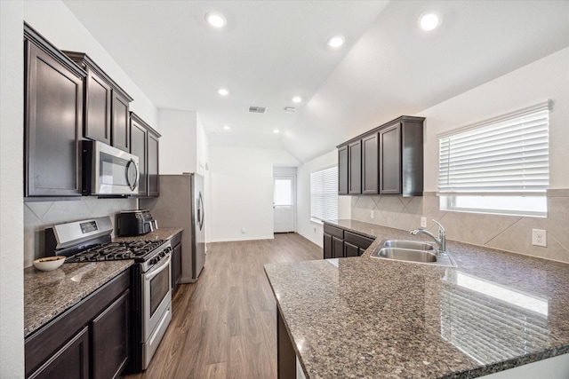 kitchen with lofted ceiling, sink, stainless steel appliances, tasteful backsplash, and light wood-type flooring