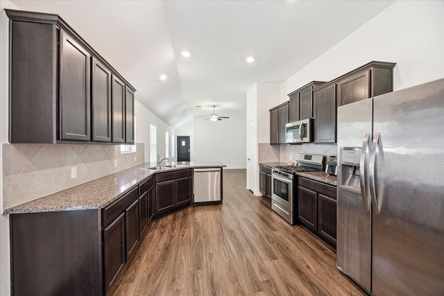 kitchen with lofted ceiling, stainless steel appliances, dark brown cabinetry, dark hardwood / wood-style flooring, and kitchen peninsula