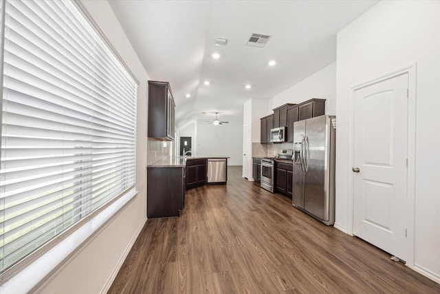 kitchen featuring dark brown cabinetry, tasteful backsplash, appliances with stainless steel finishes, dark hardwood / wood-style flooring, and ceiling fan