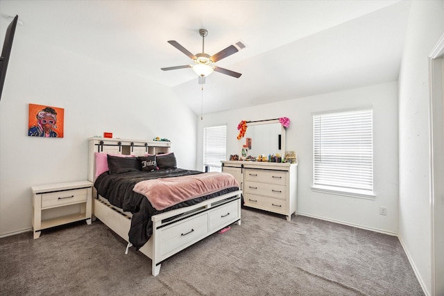 bedroom with multiple windows, vaulted ceiling, ceiling fan, and dark carpet