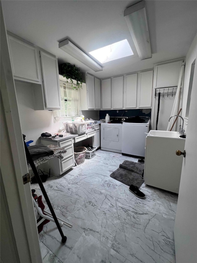 kitchen with a skylight, sink, washer and clothes dryer, and white cabinets