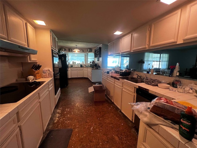 kitchen with tile counters, black appliances, kitchen peninsula, and sink