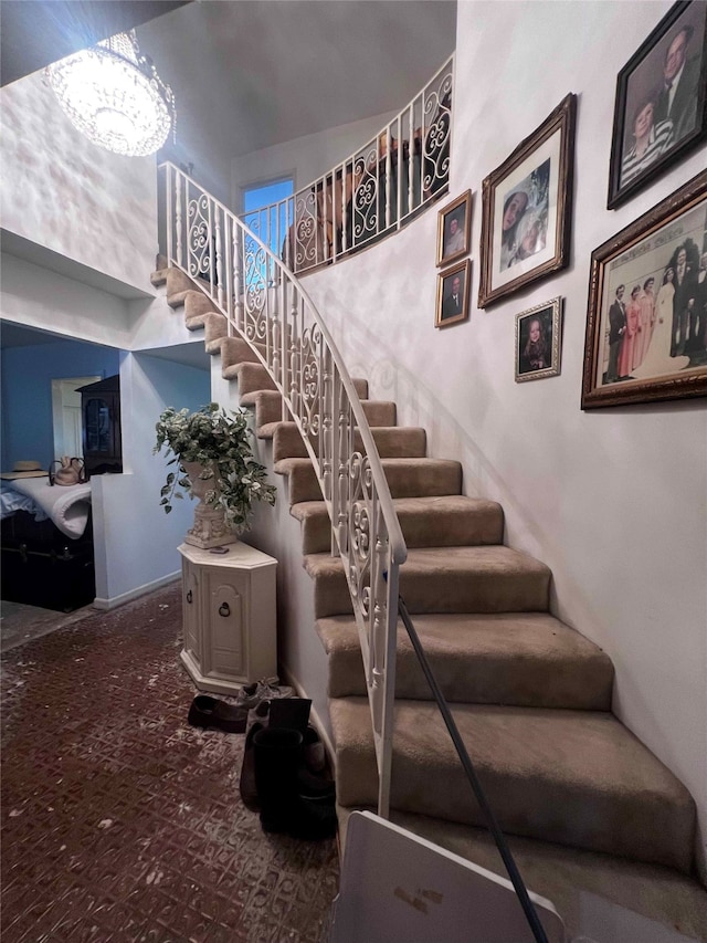 stairway featuring a towering ceiling, an inviting chandelier, and carpet