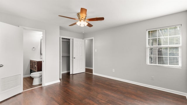 unfurnished bedroom featuring dark wood-type flooring, a closet, ceiling fan, and ensuite bathroom