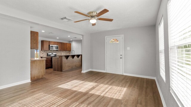 unfurnished living room featuring hardwood / wood-style flooring, sink, and ceiling fan