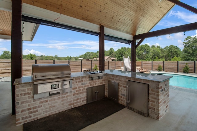 view of patio / terrace with grilling area, exterior kitchen, and a fenced in pool