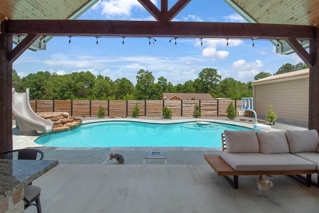 view of pool featuring outdoor lounge area, a water slide, and a patio