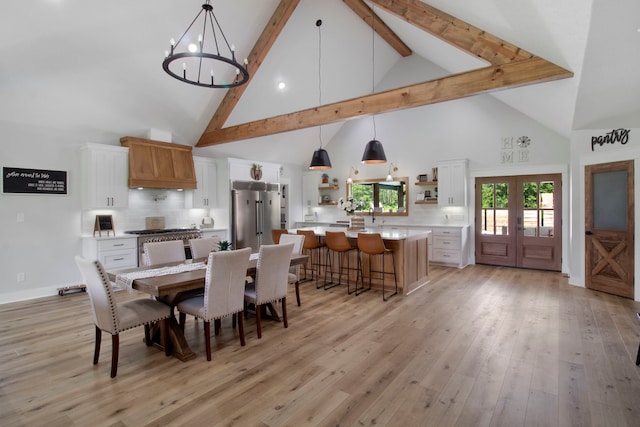 dining space featuring an inviting chandelier, light hardwood / wood-style flooring, french doors, and high vaulted ceiling