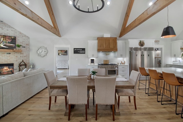 dining room with high vaulted ceiling, a brick fireplace, and beamed ceiling