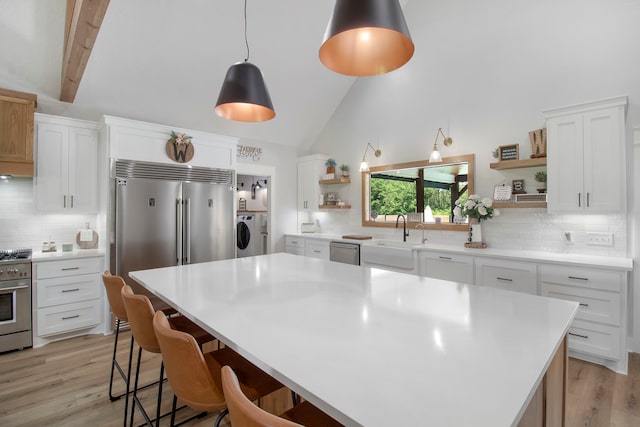 kitchen featuring white cabinetry, backsplash, separate washer and dryer, high vaulted ceiling, and a center island