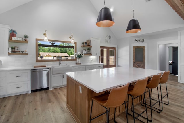 kitchen featuring white cabinetry, decorative backsplash, stainless steel dishwasher, and a kitchen island