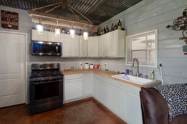 kitchen with stainless steel appliances, sink, white cabinetry, and decorative light fixtures