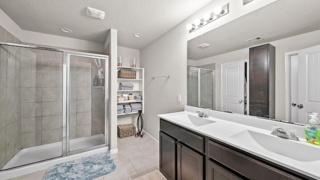 bathroom with tile patterned flooring, vanity, a shower with door, and a textured ceiling