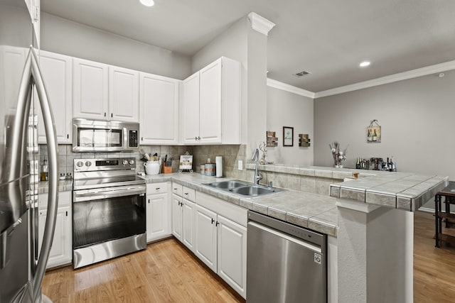 kitchen featuring white cabinetry, sink, light hardwood / wood-style flooring, kitchen peninsula, and appliances with stainless steel finishes