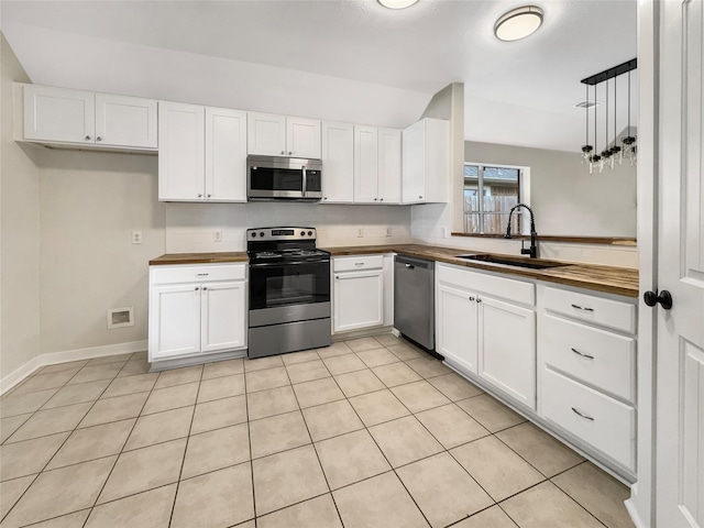 kitchen with appliances with stainless steel finishes, white cabinetry, sink, and light tile patterned floors