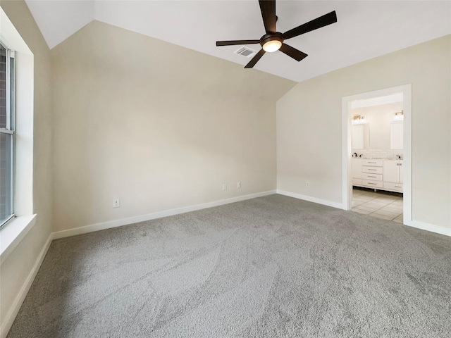 carpeted spare room with ceiling fan and vaulted ceiling